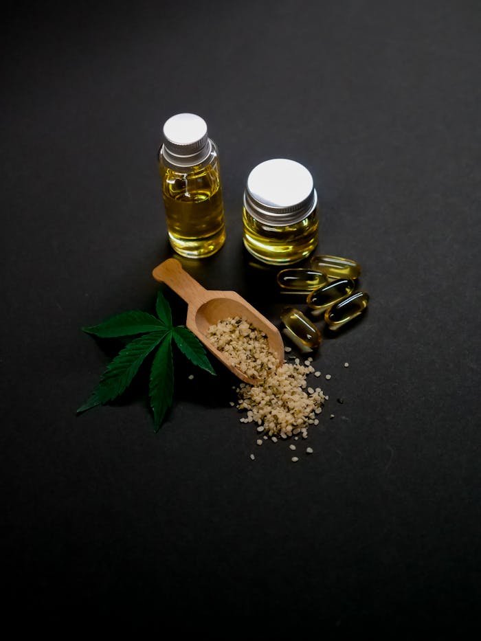 Image of cannabis oil, hemp seeds, and capsules on a dark background with green leaves.