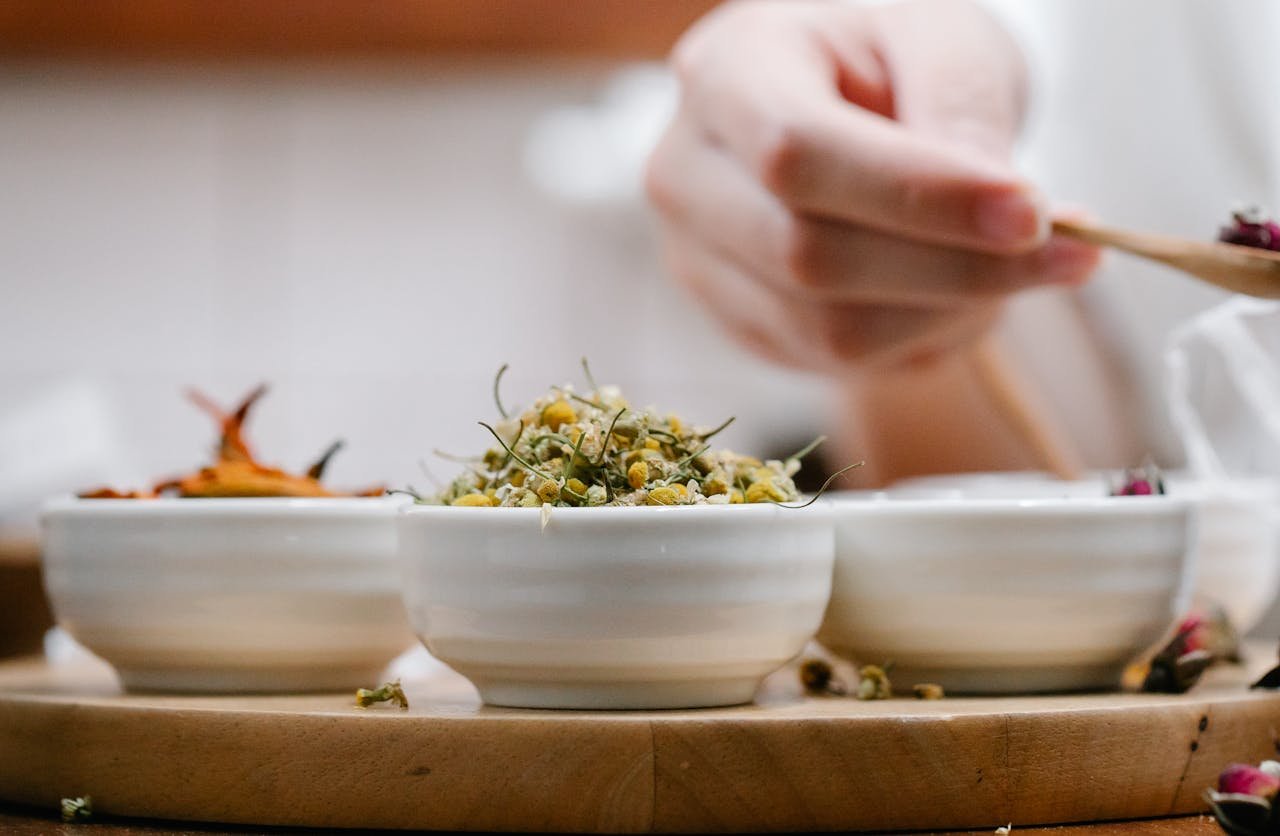 creative-03 A detailed close-up of hands preparing herbal ingredients in ceramic bowls, highlighting natural aromas.